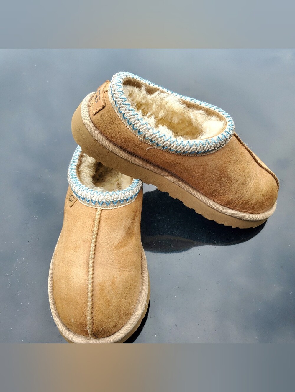 The image shows a pair of tan suede UGG Tasman Sand/Santorini Slippers featuring